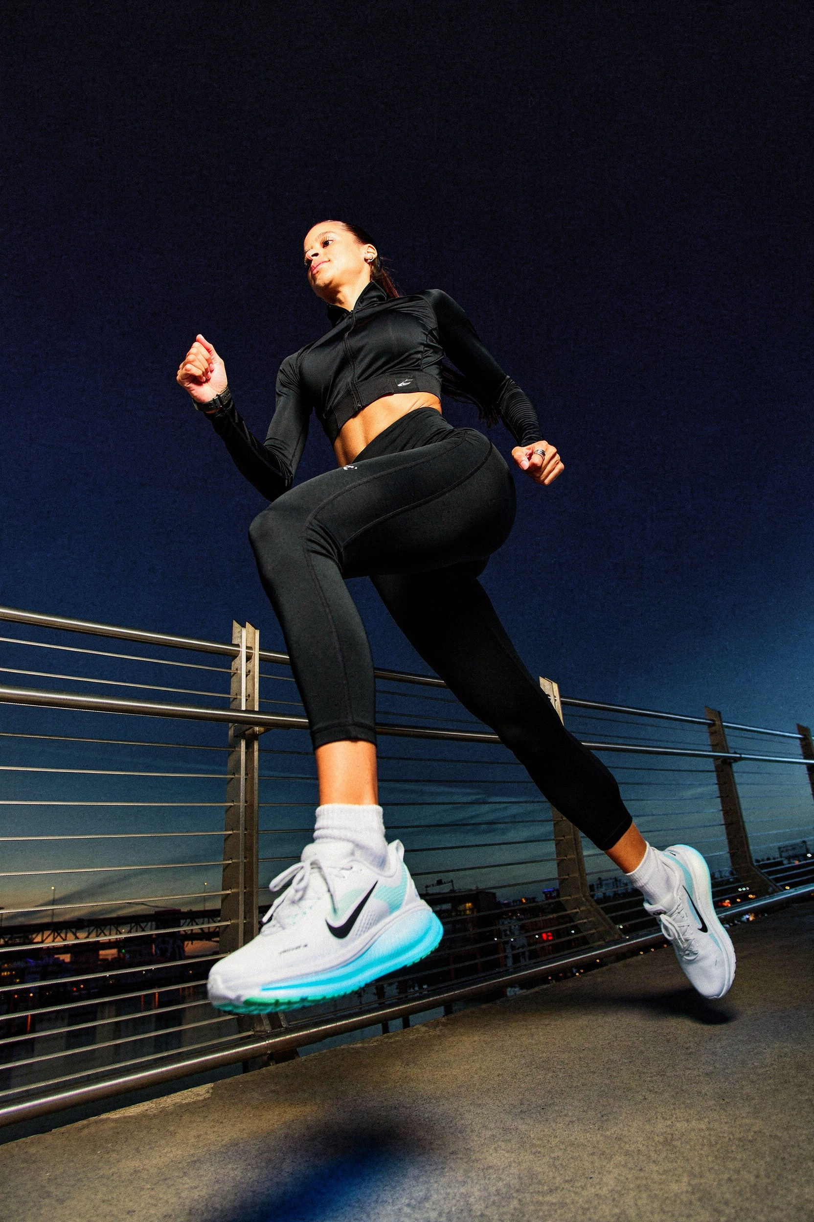Athletic woman sprinting on night bridge, teal shoes