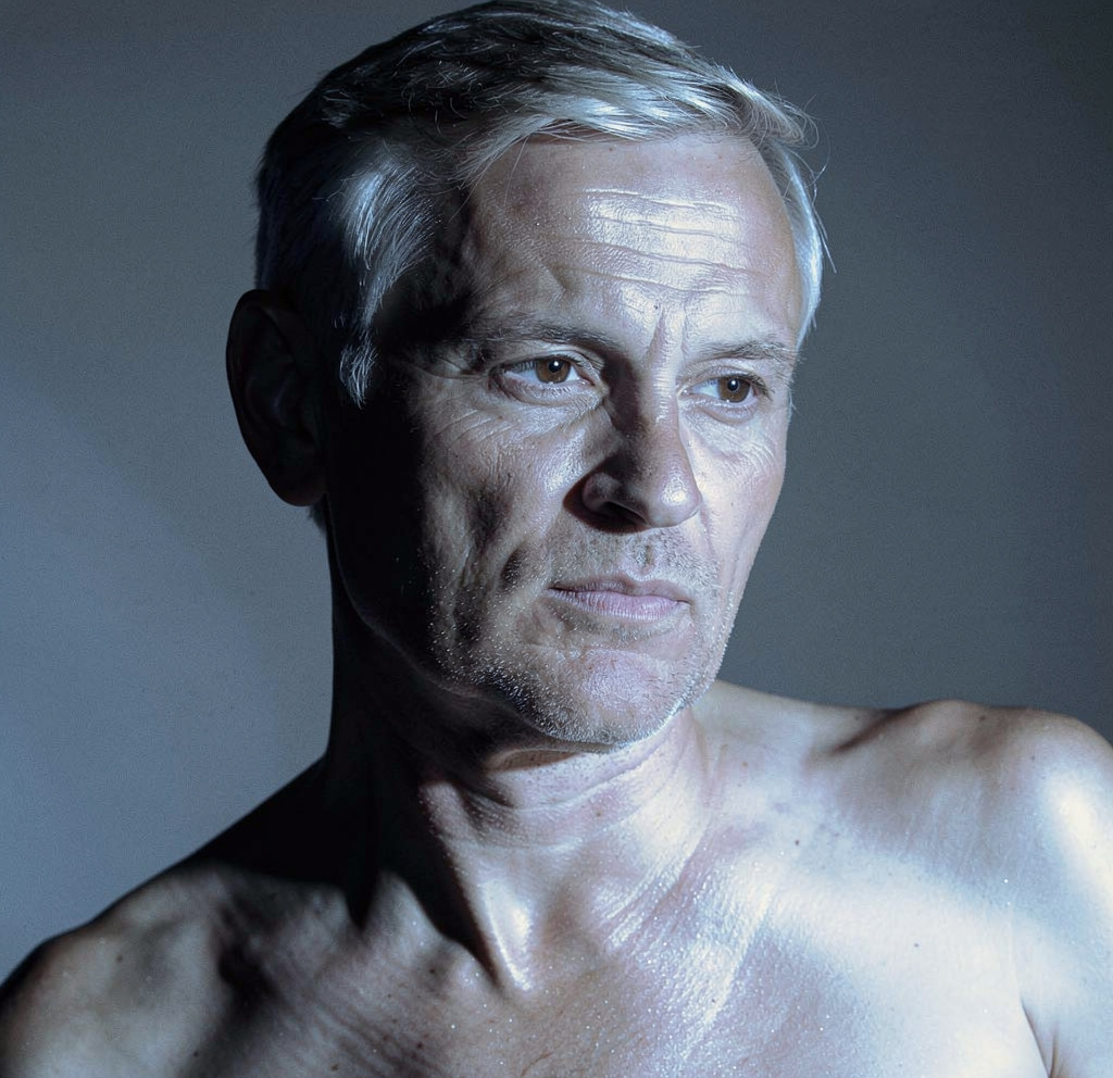 Contemplative silver-haired man in cool chiaroscuro