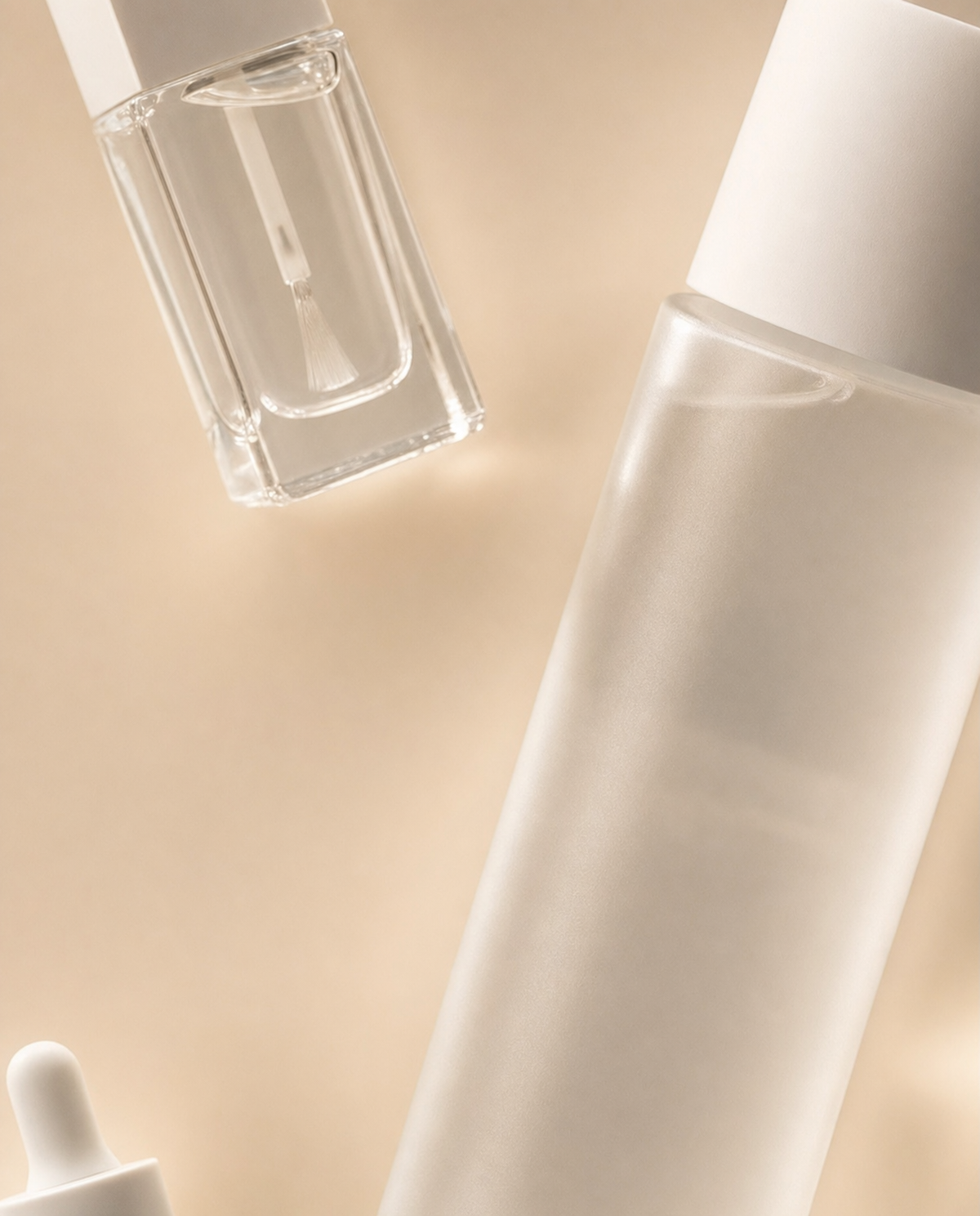 Frosted glass nail care bottles on warm beige