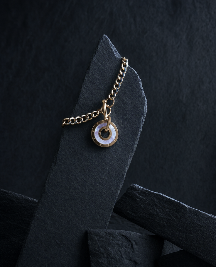 Gold chain necklace with circular pendant on slate