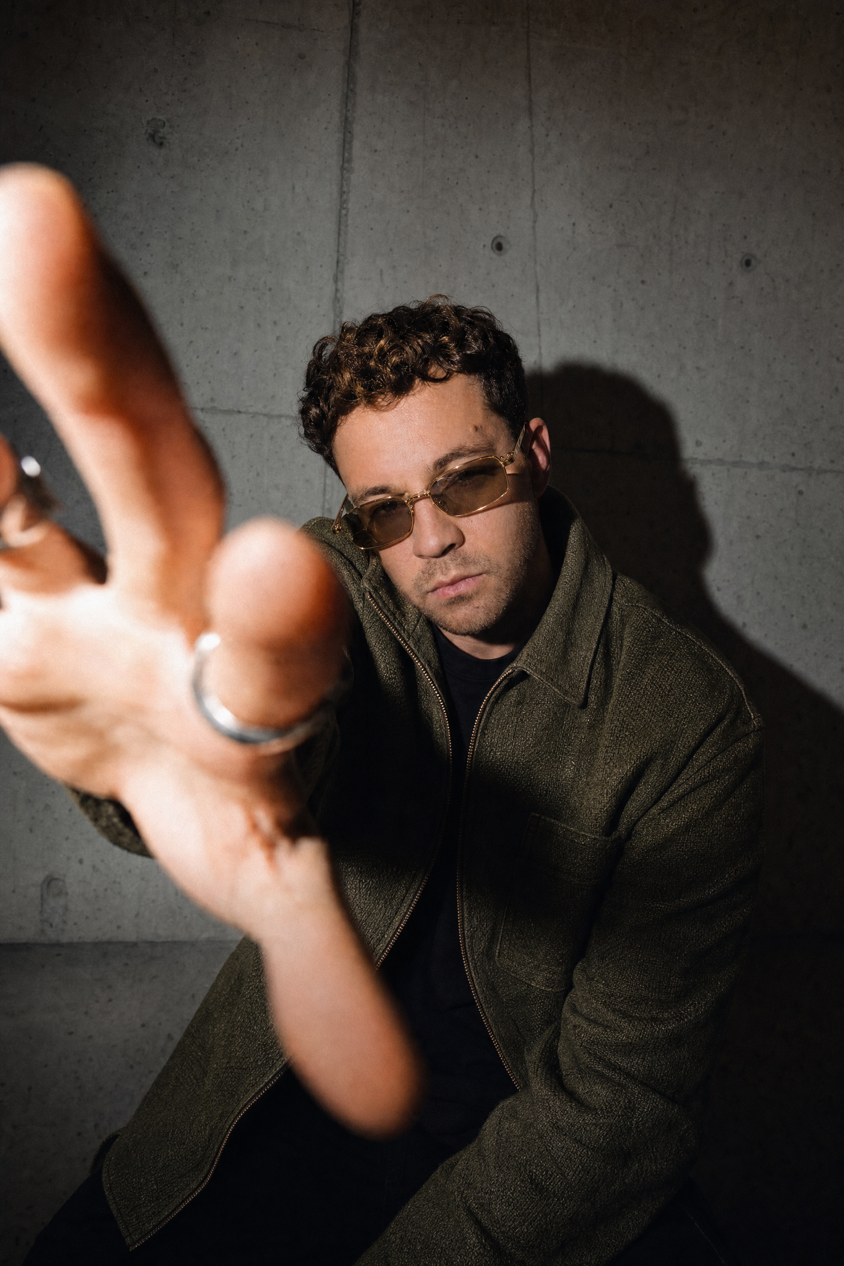 Man with gold-framed sunglasses reaching forward