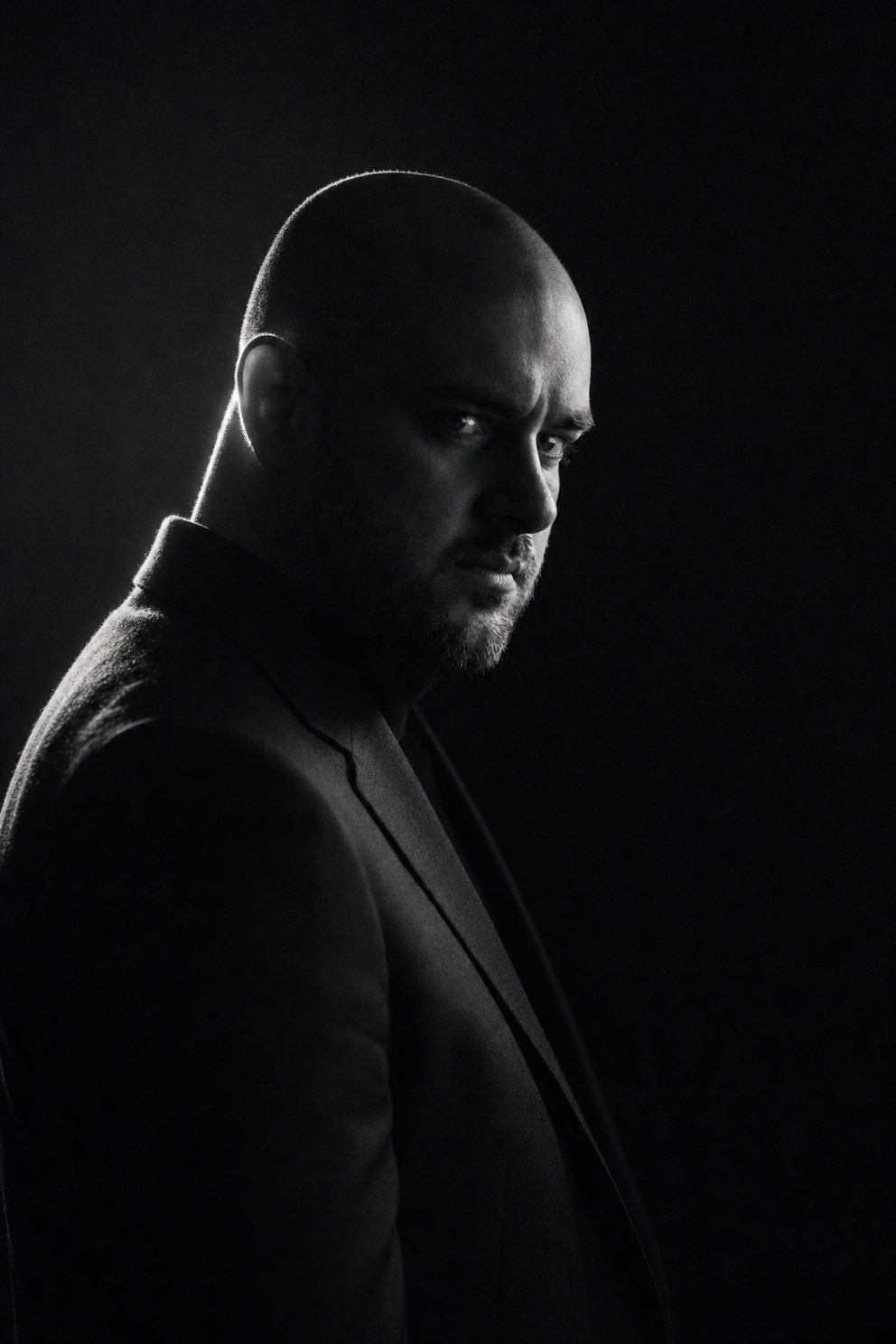 Neo-noir rim-lit bald bearded portrait