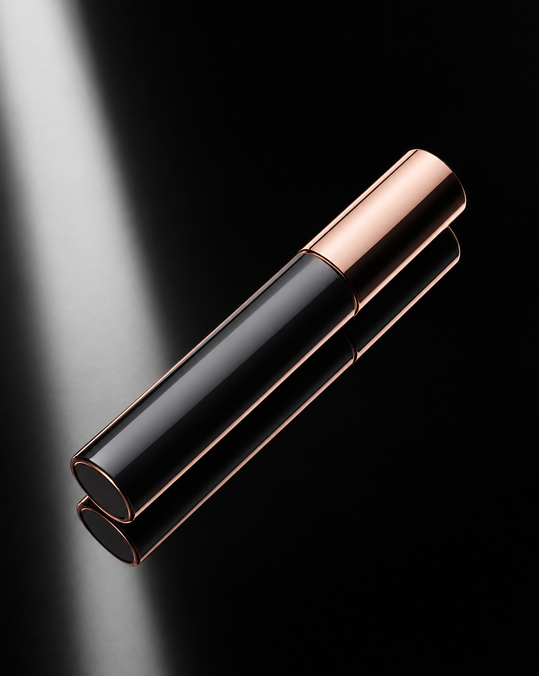 Rose-gold and black mascara tube on glossy charcoal