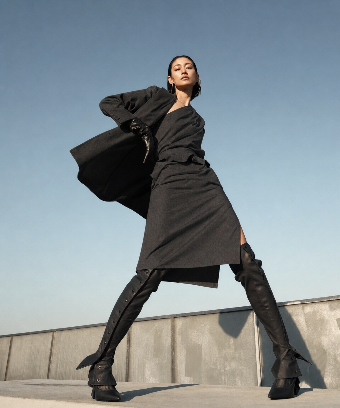 Tall female model in charcoal coat, rooftop low pose