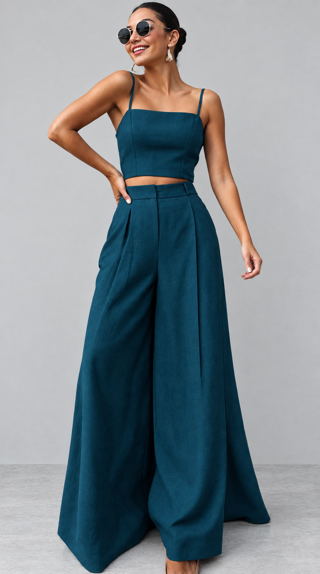 Woman in deep teal cropped top and pleated trousers