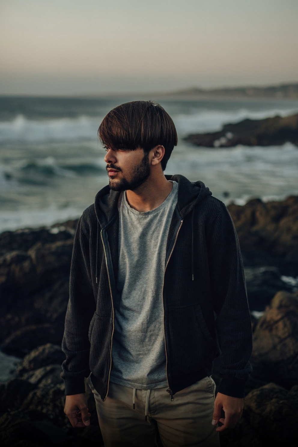 Young man in charcoal hoodie on dark rocks — Flux 2 Pro