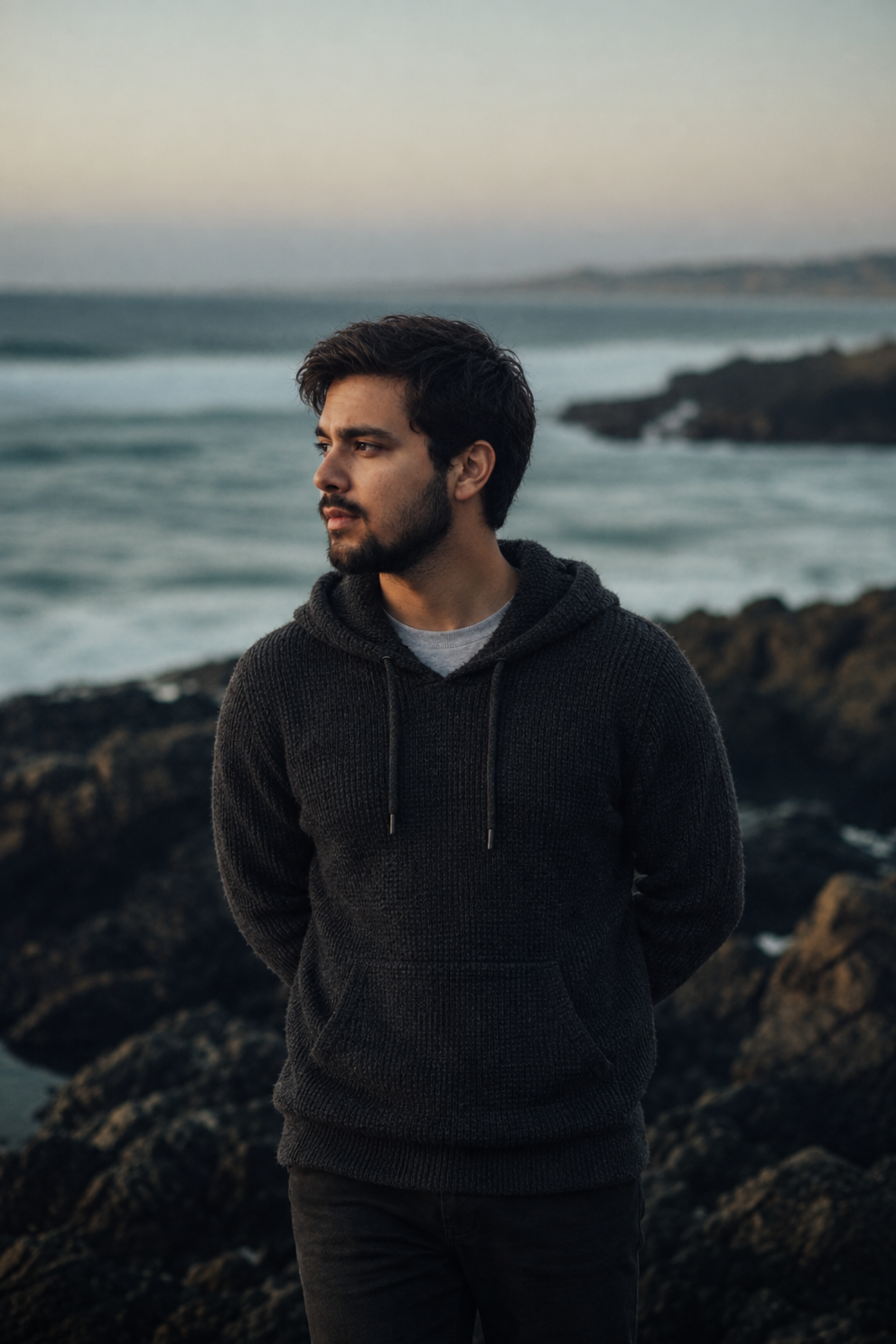 Young man in charcoal hoodie on dark rocks