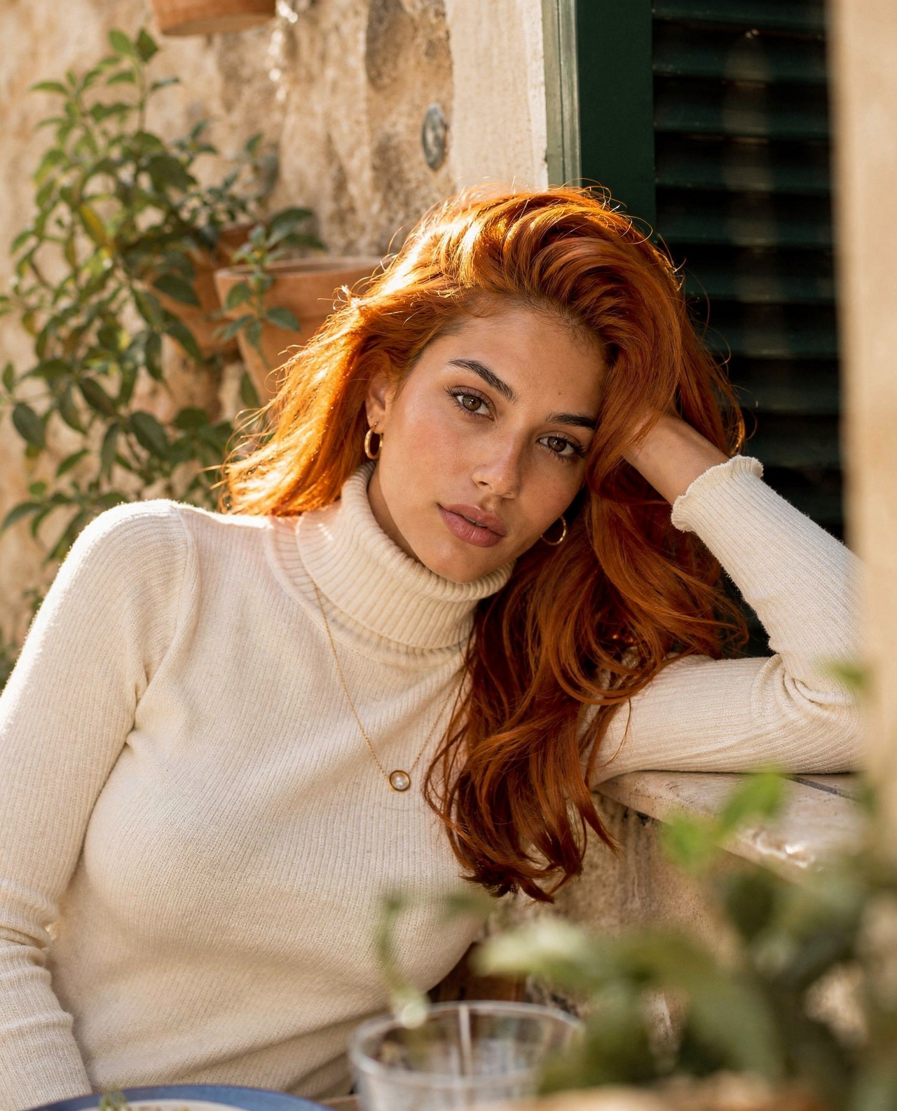 Young woman in cream turtleneck by stone wall